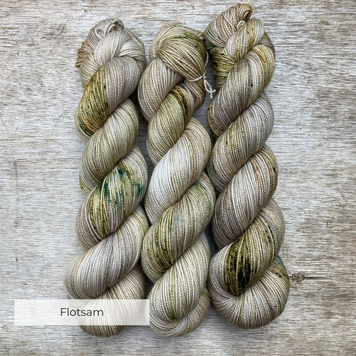 Three skeins of yarn in a neutral stone splashed with moss