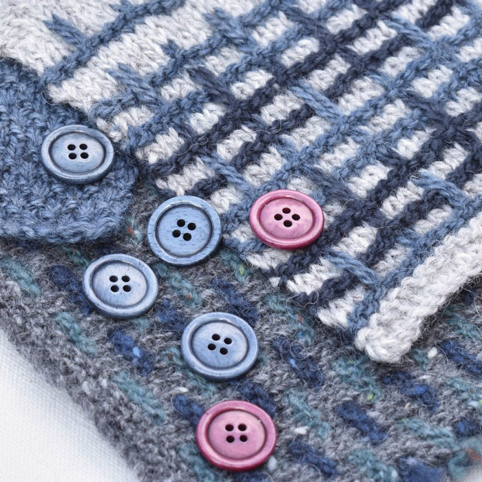 A scattering of blue and pink buttons across some knitting samples