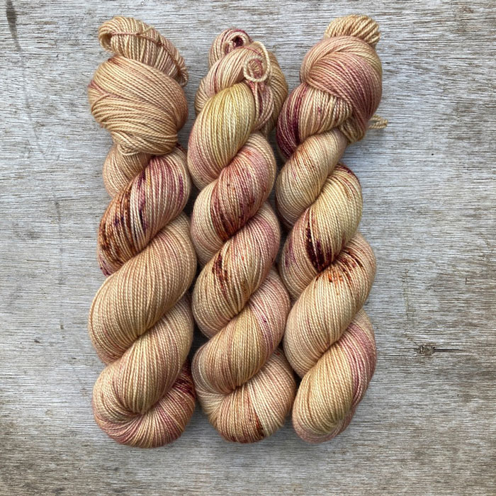 Golden, creamy yellow yarn splashed with orange and pink and wound into skeins