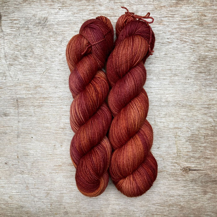 Two skeins of yarn a golden burgundy colour