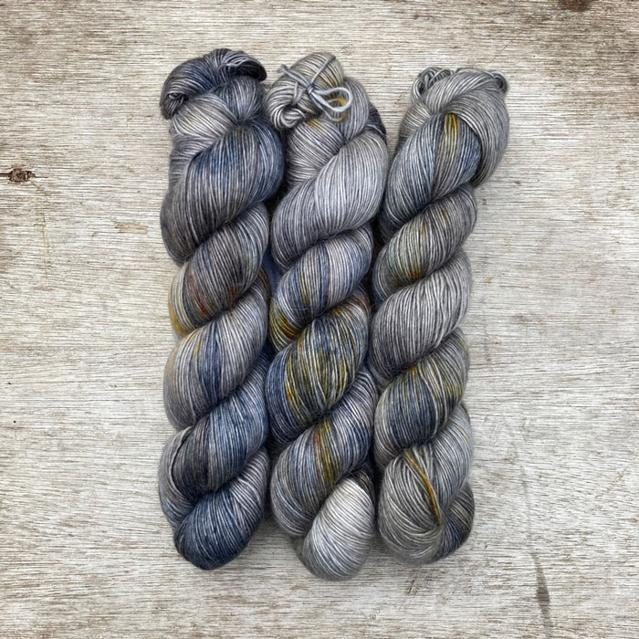 Three skeins of soft yarn in shades of silver, blue and gold
