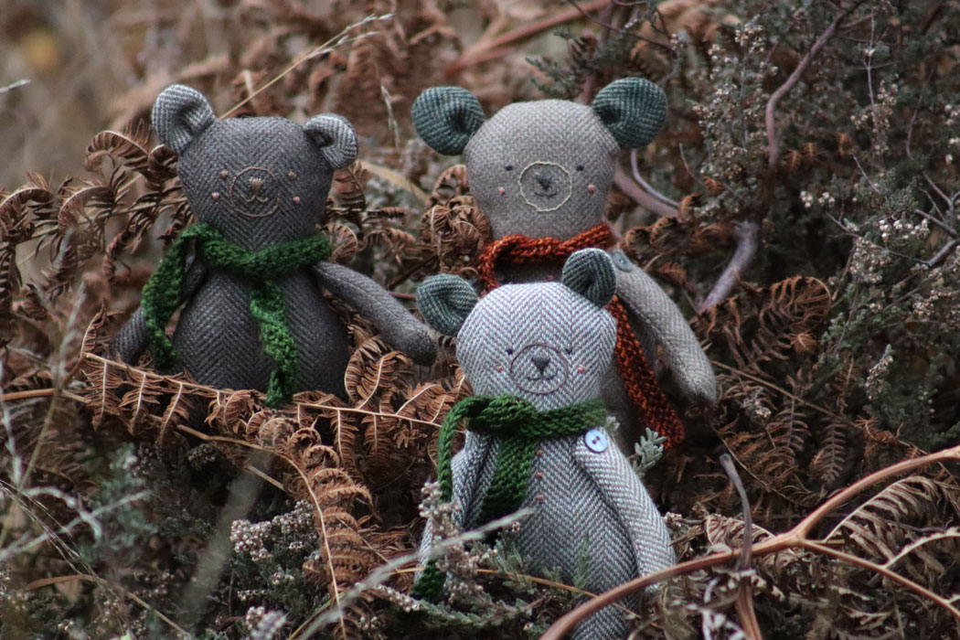 Three handmade woollen bears sitting in bracken