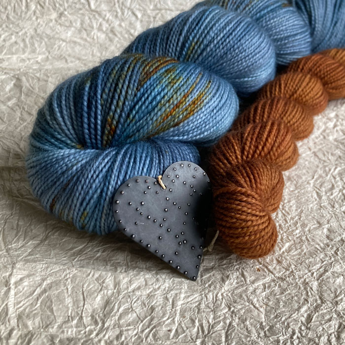 Two skeins of sock yarn on a crinkly background