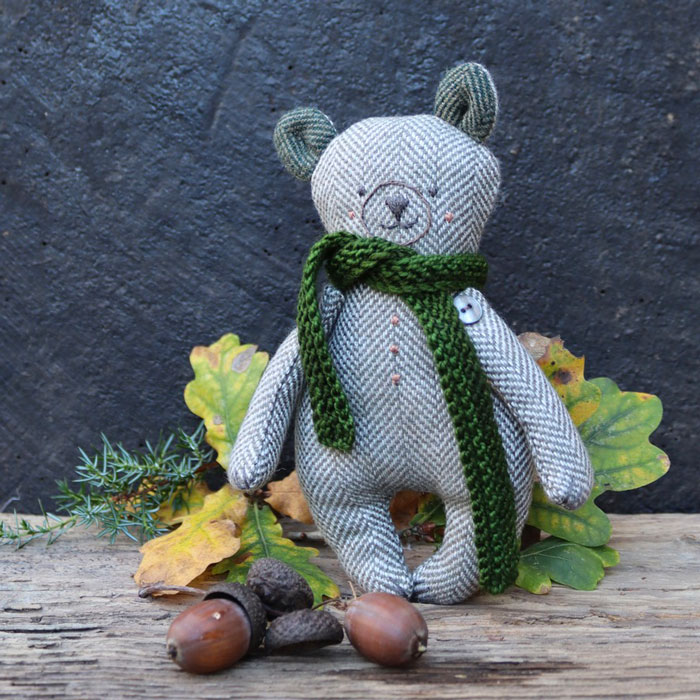 A soft toy bear surrounded by acorns and oak leaves