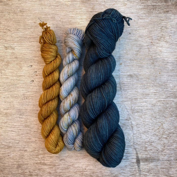 Two mini skeins in gold and icy blue with gold splashes and a full 100g in dark teal