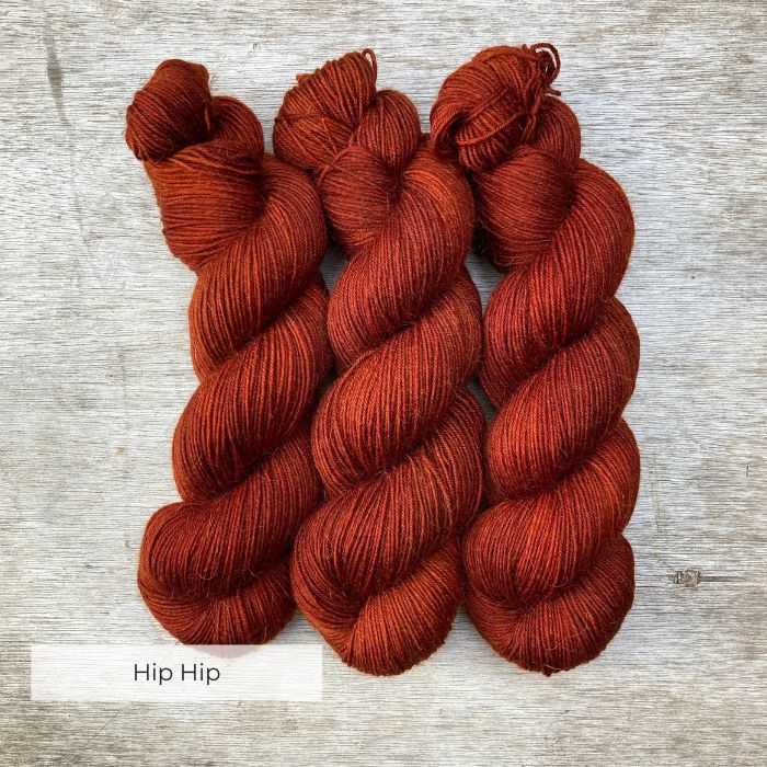 Three plump skeins of burnt orange red yarn