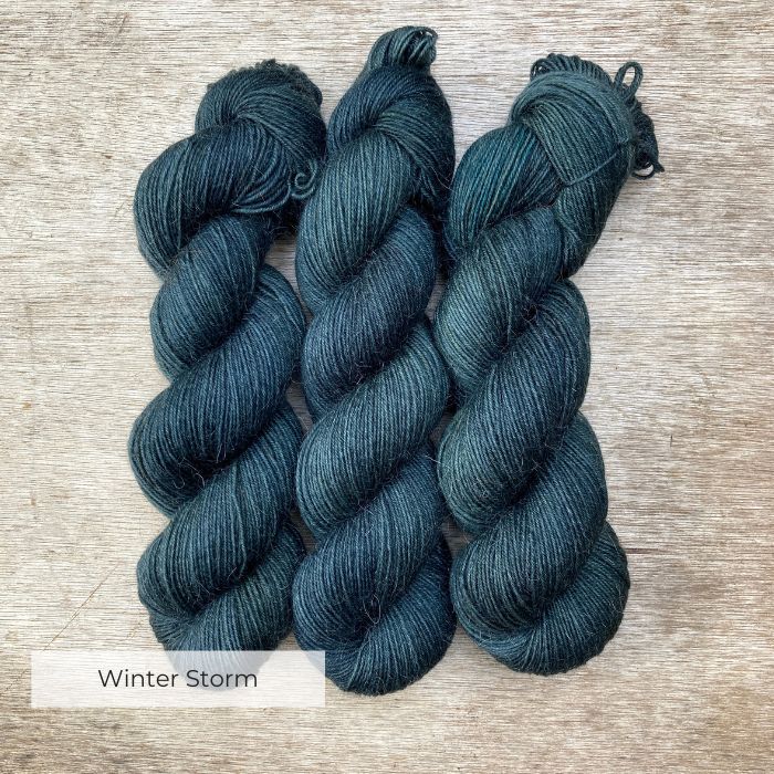 Three dark teal blue skeins of yarn