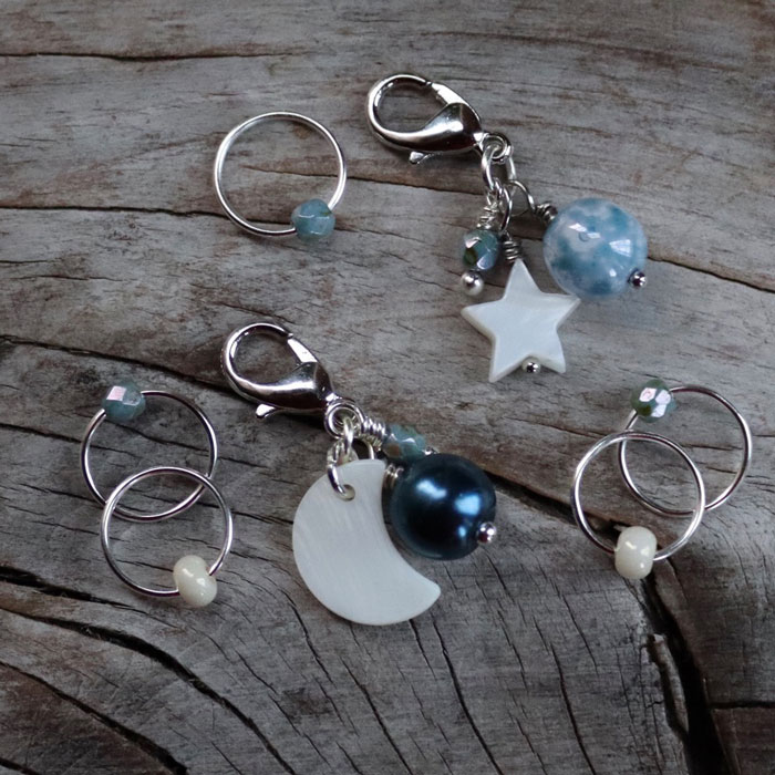A selection of stitch markers and progress keepers on a grey wooden background