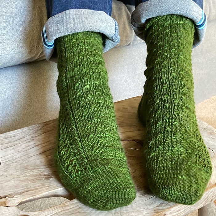 A ladies feet on a stool wearing a pair of nubbly wool socks