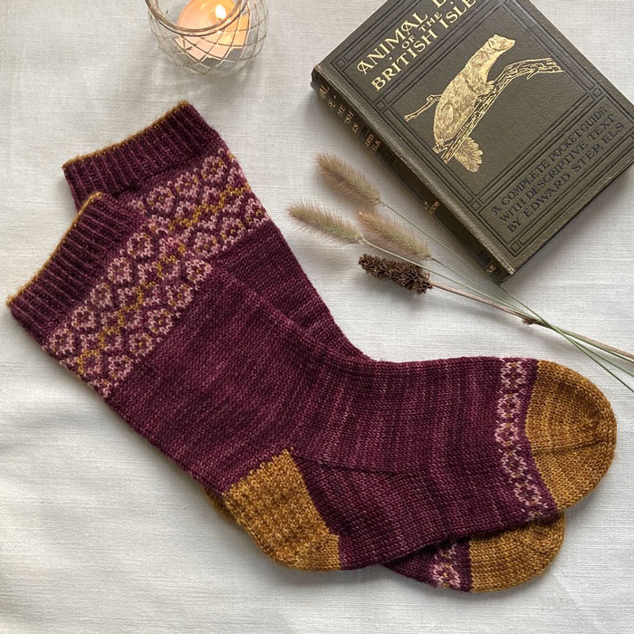 A pair of hand knit socks with pattern at the toe and cuff