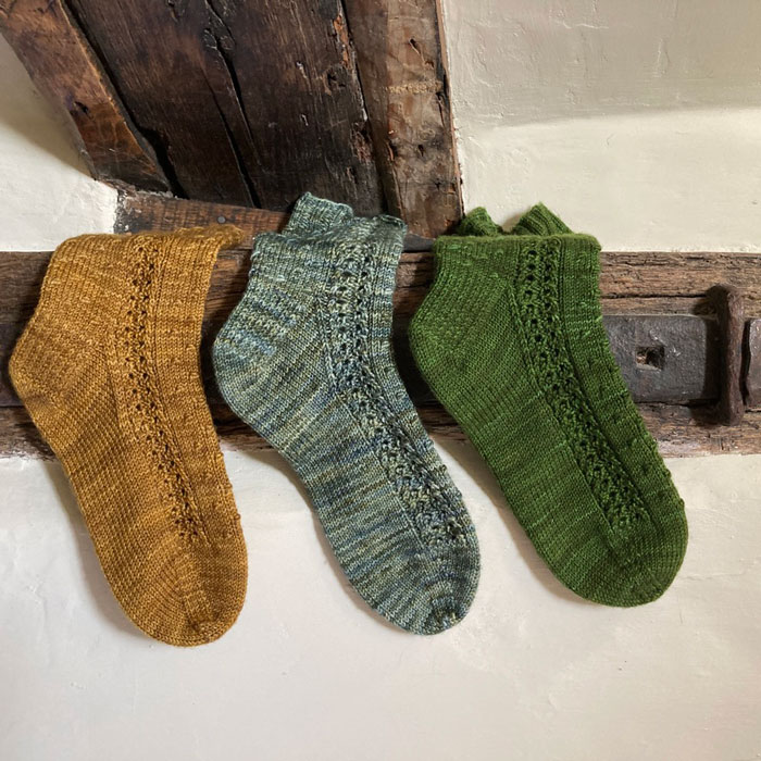 Three socks laid over a wooden beam