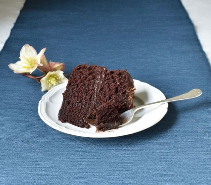 A slice of moist chocolate cake on a white plate