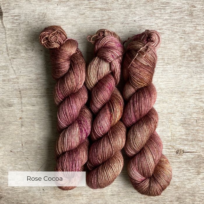 Three skeins of silky wool in shades of pink , plum and milky coffee