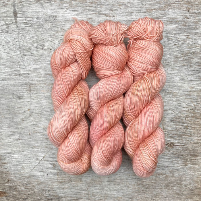 Three skeins of pink yarn with faint yellow speckles