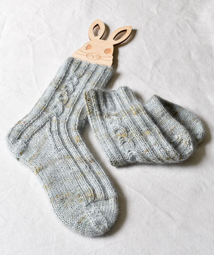 A pair of hand knit fluffy socks on a rabbit shaped blocker