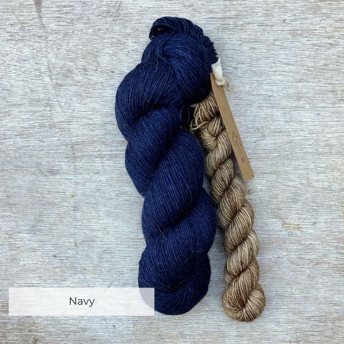 A full skein of Merino & Mohair sock yarn in a deep navy blue colour with a mini in a speckled buff