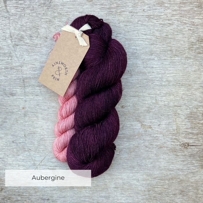 A full skein of Merino & Mohair sock yarn in a deep aubergine colour with a mini in pink