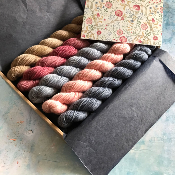 Five mini skeins of yarn in a tissue wrapped box with the inspiration card