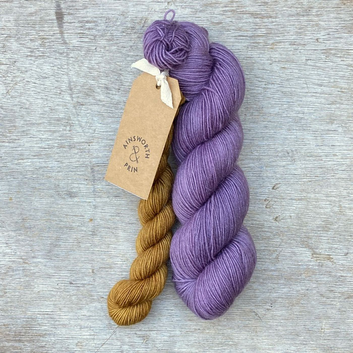 A full skein of Merino& Mohair sock yarn in a lavender colour with a mini in mustard