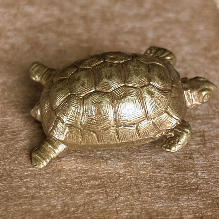 A pressed metal brooch in the shape a tortoise