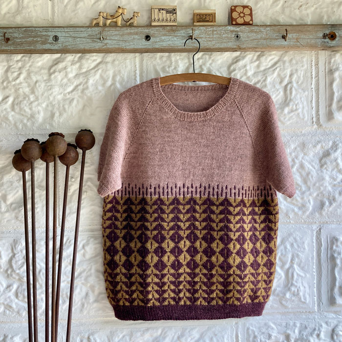 A short sleeved top with a geometric pattern on the body in plum, gold and pink
