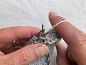 Spare needle inserted into first stitch on left hand needle as if to knit . Yarn wrapped around the needle as if to knit