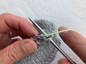 Yarn pulled through purl stitch.