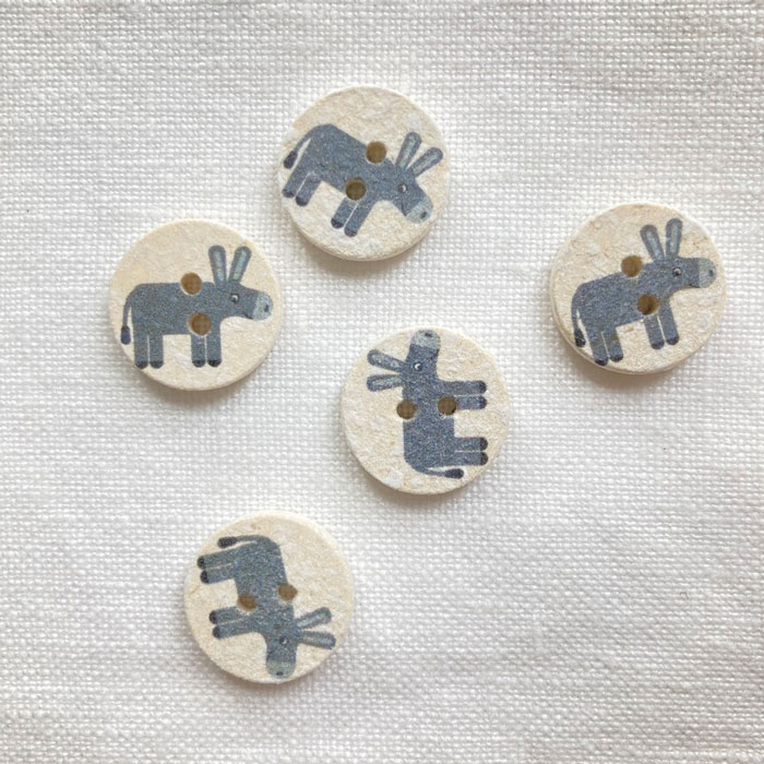 Five buttons made from recycled coconut shell printed with the image of a grey donkey