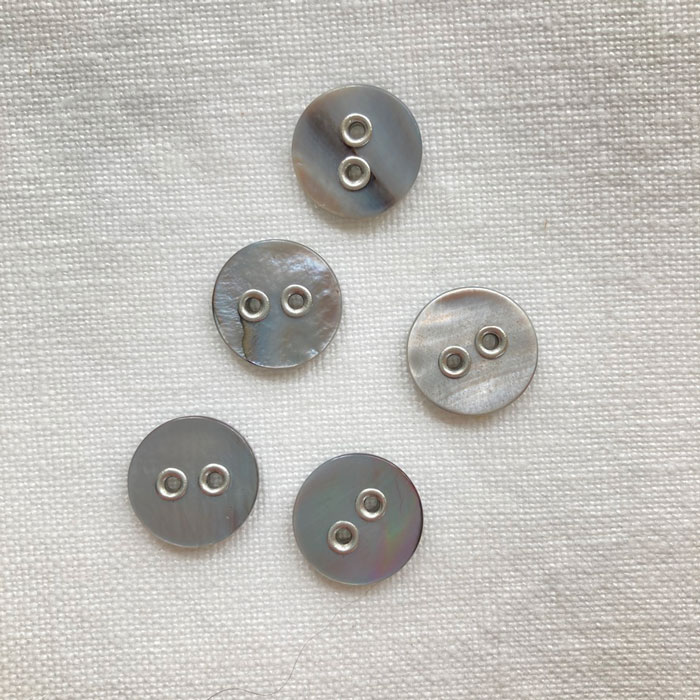 Five grey shell buttons with silver coloured metal holes