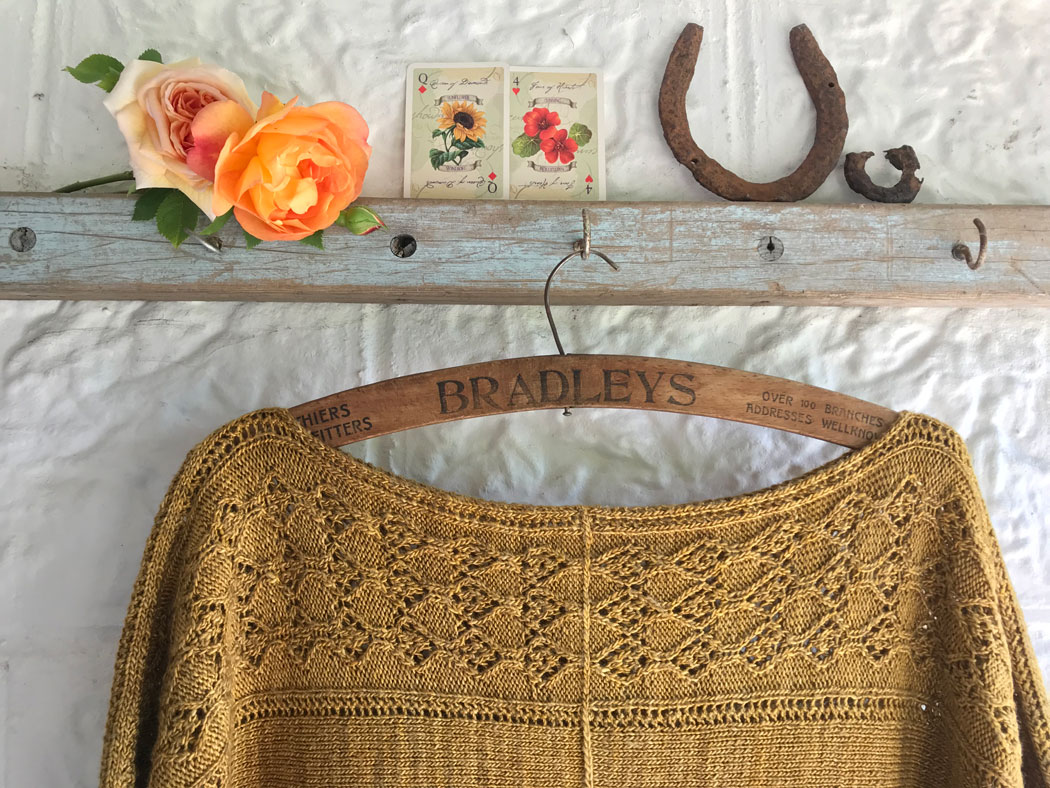 Yellow loose top hung from blue rail. Roses, flowered playing cards and horse shoes on top of rail