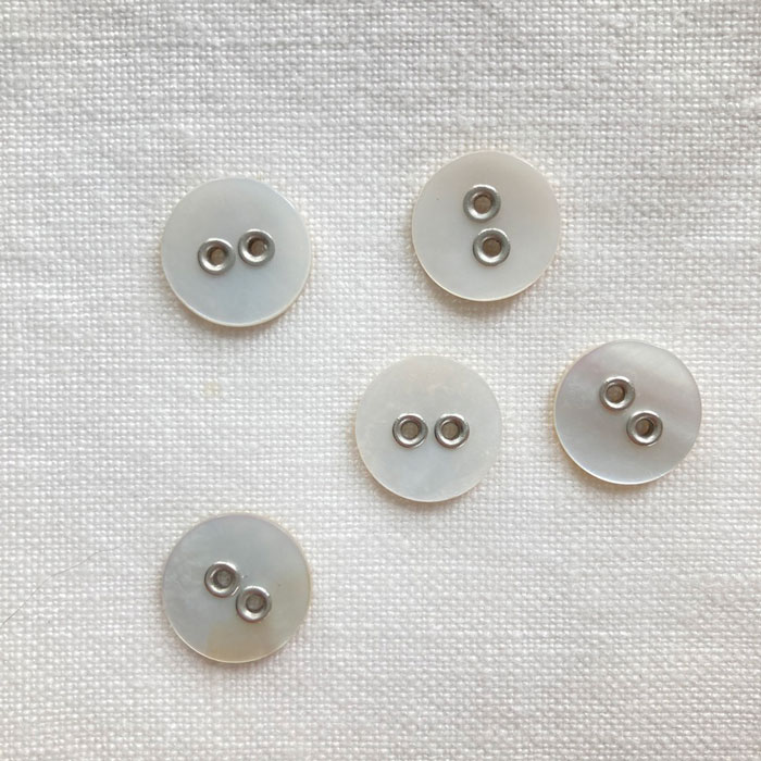 Five white shell buttons with silver coloured metal holes