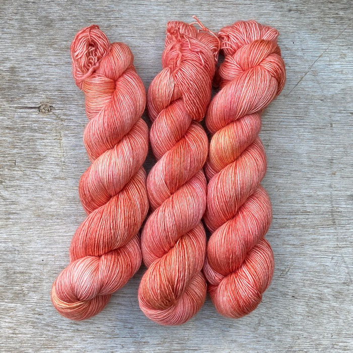 Three skeins of a deep coral yarn