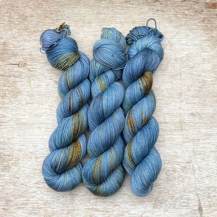 Three skeins of sock wool in cool blue splashed with gold