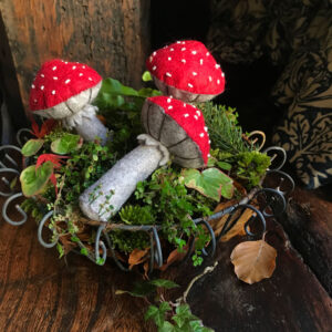 three felt toadstools in a mossy wire bowl