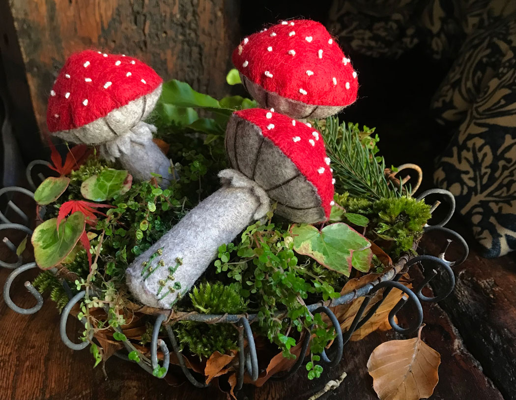 three felt toadstools in a mossy wire bowl
