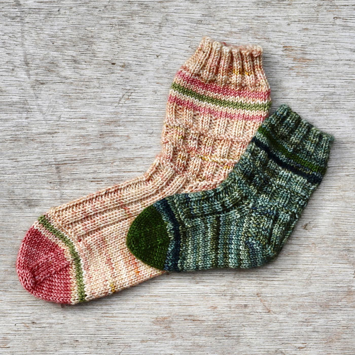 Two children's socks in different sizes. one in pink and the smaller one in green