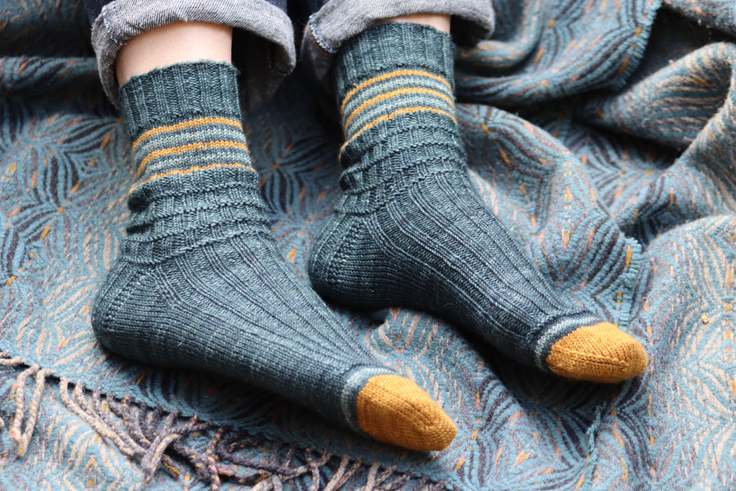 A pair of feet in hand knit socks on a blanket