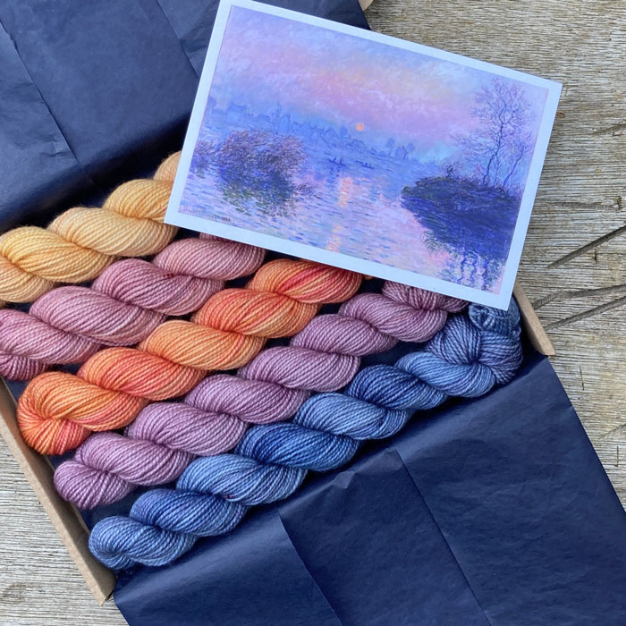 A tissue lined box with 5 sunset coloured mini skeins and the postcard inspiration