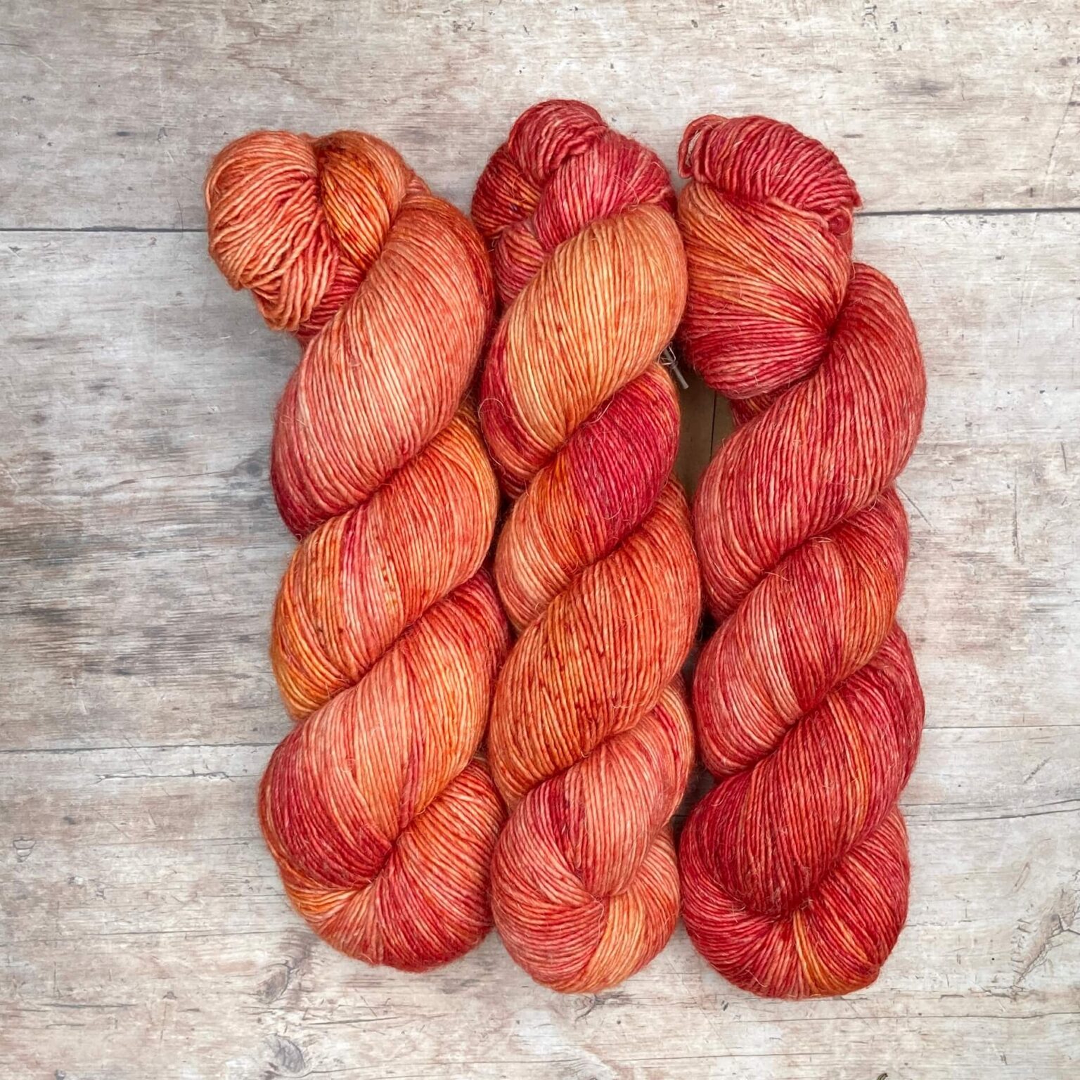 skeins of merino and linen yarn in shades of bright peach, shocking pink and orange