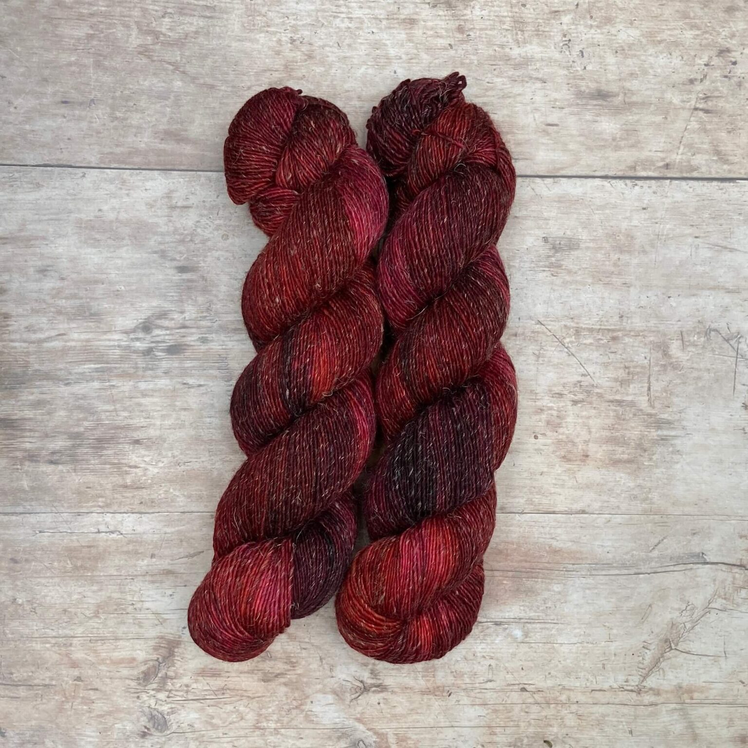 skeins of Merino and linen yarn in a rich red and dark pink