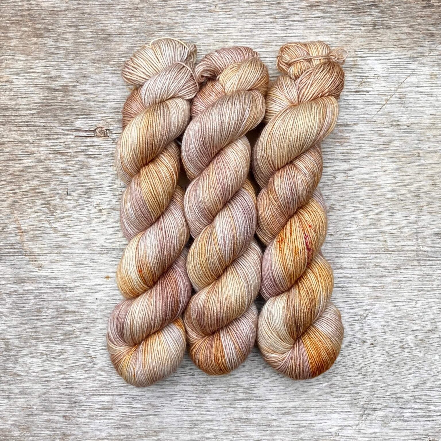 Three skeins cream, pink and gold merino and mohair sock yarn