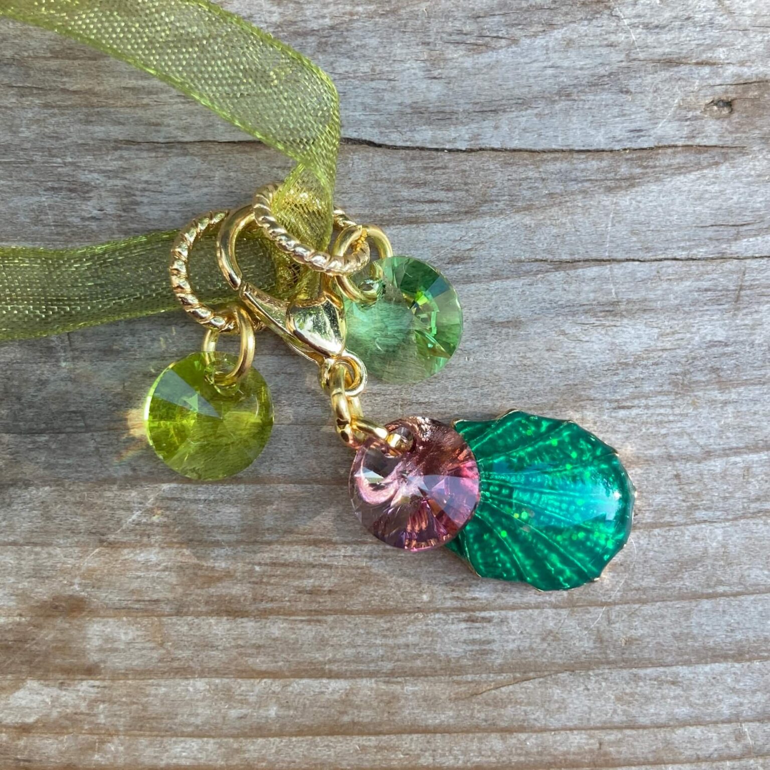 A green shell removable stitch marker with two green crystal markers
