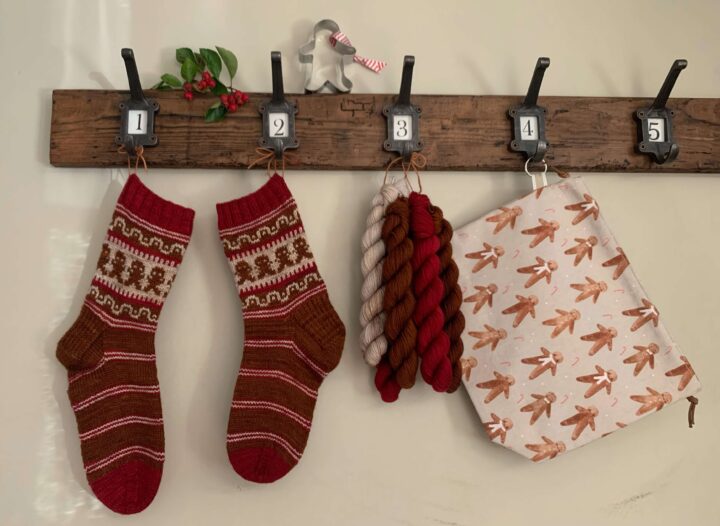 A pair of I'm a gingerbread man socks with a themed workbag and yarn hanging from hooks