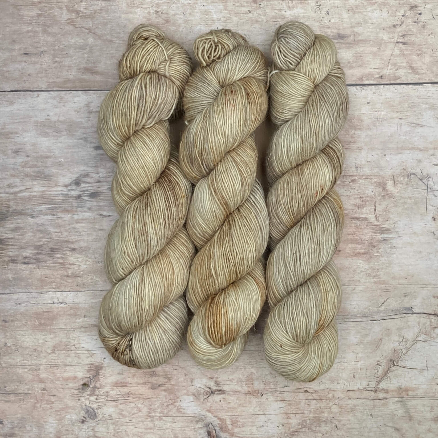 Three skeins of merino and linen in buttercream, coffee and gold