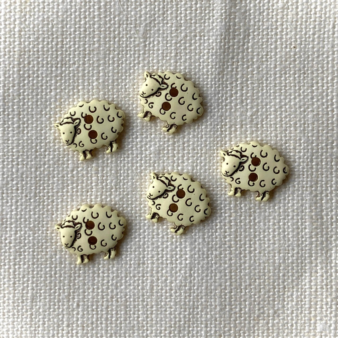 Five cream sheep shaped buttons