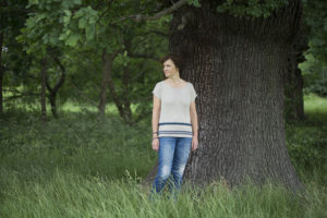 A woman standing under a tree wearing a linen knitted jumper
