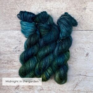 Three skeins of plump DK wool in dark blues, emeralds and lime
