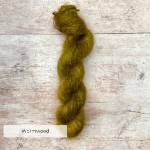One skein yellow / green mohair silk yarn on pale wood background.