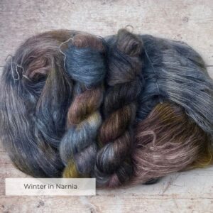 Three skeins of blue, yellow and orange mohair and silk lace yarn on pale wood background