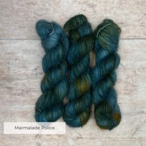 three skeins of mohair and silk lace in blue and dark teal yarn splashed with marmalade orange